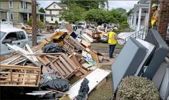  ?? Craig Ruttle/Associated Press photos ?? Utility workers work among debris from flood damage caused by the remnants of Hurricane Ida in Manville, N.J., on Sunday. Flood-stricken families and business owners across the Northeast are hauling waterlogge­d belongings to the curb as cleanup moves into high gear.