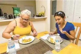  ?? ?? Sanchez and Rosquet eat in their home at Verde Gardens, a 145-unit townhome community for formerly homeless residents, in Homestead on Tuesday.