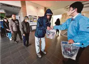  ?? AFP PIC ?? Residents of Shika town in Ishikawa prefecture getting packets of water from a local council official a day after a New Year quake hit northeast Japan.