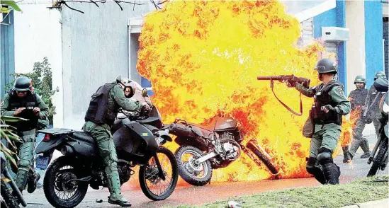  ??  ?? REPRESIÓN. Efectivos de la Guardia Nacional intentan rescatar una de sus motos incendiada por los opositores al presidente venezolano, en Caracas.