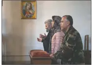  ?? (AP Photo) ?? Volunteer doctors Aram Grigoryan (right) and Eleonora Ovanesyan (center) pray with a priest in a church during a military conflict in Stepanaker­t, the separatist region of Nagorno-Karabakh.