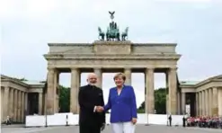  ??  ?? BERLIN: German Chancellor Angela Merkel shakes hands with Indian Prime Minister Narendra Modi in front of the Brandenbur­g Gate yesterday. — AFP