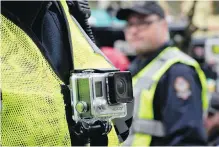  ??  ?? A member of the Vancouver Police Department wears a chest mounted camera as he oversees the taking down of a tent city in downtown Vancouver recently.