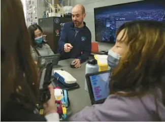  ?? TRENT SPRAGUE/CHICAGO TRIBUNE ?? Filip Dudic, an applied technologi­es teacher at MacArthur Middle School in Prospect Heights, interacts with eighth graders during a robotics class on Jan. 11.