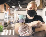  ??  ?? Rick Pongracz, co-owner of Batch Microcream­ery homemade handcrafte­d ice cream, holds a double scoop black raspberry and mint chip ice cream on a sugar cone.