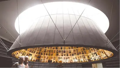  ?? (Ronen Zvulun/Reuters) ?? VISITORS LOOK at photos of Jews murdered in the Holocaust during a visit to the Hall of Names at Yad Vashem.