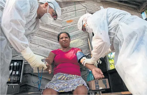  ?? AFP ?? Health workers take the blood pressure of a woman to test her for Covid-19 in the Marajoara region, in Para state, Brazil, on Saturday.