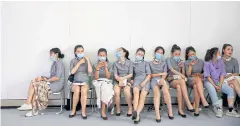 ??  ?? A MOMENT TO BREATHE: Ushers wearing face masks take a rest on the sidelines of the Auto China show, in Beijing, China, yesterday.