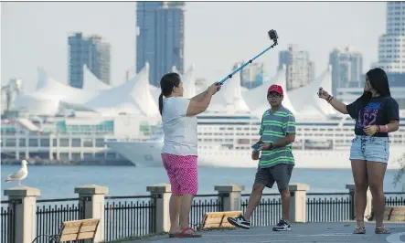  ?? GERRY KAHRMANN/ FILES ?? Tourists take photos along the seawall in Vancouver’s Stanley Park. The low Canadian dollar is a huge incentive for tourism, particular­ly when it comes to attracting American visitors. In British Columbia, a spokeswoma­n for Tourism Whistler said the...