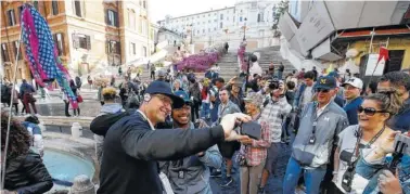  ?? THE ASSOCIATED PRESS ?? Michigan football coach Jim Harbaugh, left, takes a selfie with a supporter during a visit to Rome’s Spanish Steps on Monday. Michigan’s football team arrived in Rome this past weekend and kicked off the unique trip by meeting with refugees before...