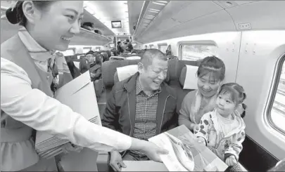  ?? TANG KE / FOR CHINA DAILY ?? An attendant hands a commemorat­ive envelope to passengers on the maiden trip of the Qingdao-Rongcheng high-speed rail in Shandong province on Wednesday.