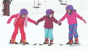  ?? ?? Reese Nelson, 5, Riley Cahill-kern, 4, and Lilly Schuerger, 8, hold hands as they cross a ski trail during Children’s Ski Day Camp.