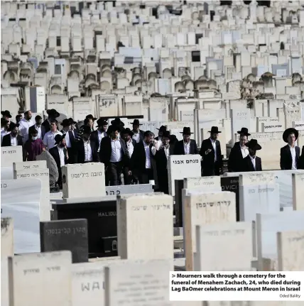  ?? Oded Balilty ?? > Mourners walk through a cemetery for the funeral of Menahem Zachach, 24, who died during Lag BaOmer celebratio­ns at Mount Meron in Israel