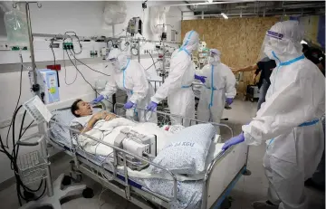  ?? (David Cohen/Flash90) ?? MEDICAL STAFF members examine a mock patient during an exercise simulating the treatment of coronaviru­s symptoms, at Ziv Medical Center in Safed, this week.