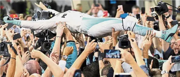  ??  ?? You raise me up: Nico Rosberg of Germany is carried through the crowd as he celebrates his Formula One championsh­ip win at the Yas Marina race track in
Abu Dhabi yesterday. — AP