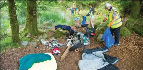  ??  ?? Volunteers cleaning up the mess left behind from a forest party.