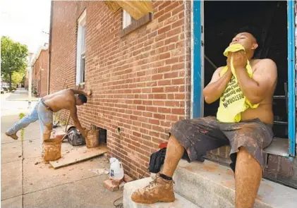  ?? AMY DAVIS/BALTIMORE SUN ?? Kevin Garcia, right, mops his face while taking a brief break Monday from excavating a basement in the 1300 block of Jackson Street in South Baltimore. Garcia and Jose Damian, left, are working for United Restoratio­n.