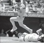  ?? Mark J. Terrill Associated Press ?? BEN ZOBRIST of the Oakland Athletics jumps over Angels catcher Chris Iannetta, who is charged with an error for failing to scoop up a squeeze bunt.