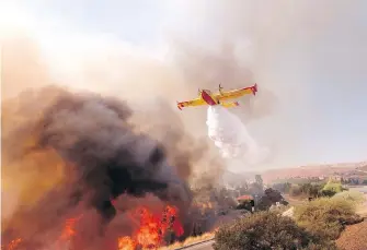  ??  ?? An air tanker drops water on a fire along the 118 Freeway in Simi Valley on Monday.