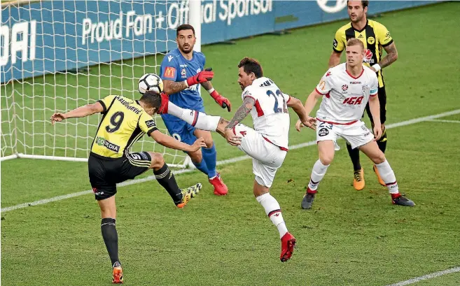  ?? GETTY IMAGES ?? Andrija Kaludjerov­ic of the Phoenix uses his head and Adelaide’s Ersan Gulum his boot in a goalmouth scramble for possession during the A-League match in Wellington last night.