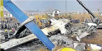  ??  ?? Rescue workers work at the wreckage of a Us-bangla airplane after it crashed at the Tribhuvan Internatio­nal Airport in Kathmandu.