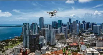  ?? Saul Martinez / New York Times ?? John Murphy, left, and Larry Shueneman of Coastal Constructi­on fly a drone over a constructi­on site at the Paramount Miami Worldcente­r tower being built in downtown Miami.