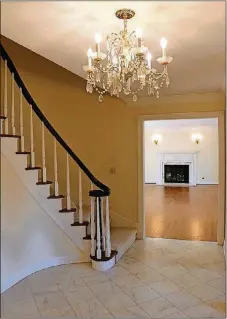  ??  ?? Formal entry opens from double doors into a grand foyer with marble flooring, a brass chandelier and curved wooden staircase.