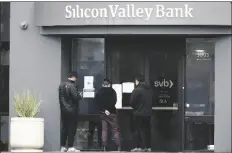  ?? JEFF CHIU/AP ?? PEOPLE LOOK AT SIGNS POSTED outside of an entrance to Silicon Valley Bank in Santa Clara, Calif., on Friday.