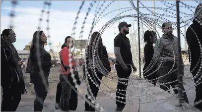  ?? Ramon Espinosa ?? The Associated Press Pedestrian­s stand near barbed wire Monday at a Mexico-u.s. border crossing as they prepare to leave Tijuana, Mexico. The United States closed off northbound traffic for several hours at the crossing to install new security barriers on Monday.
