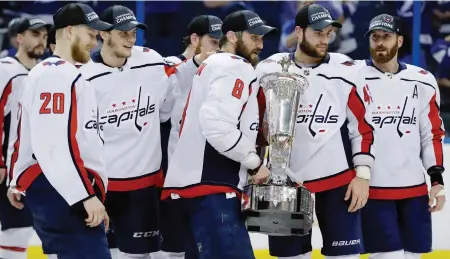  ?? CHRIS O’MEARA, THE ASSOCIATED PRESS ?? Surrounded by teammates, Washington captain Alex Ovechkin carries the Prince of Wales Trophy Wednesday after the Capitals demolished the Tampa Bay Lightning 4-0 in Game 7 of the NHL’s Eastern Conference final in Tampa, Florida.