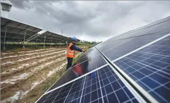  ?? PHOTOS BY WU GANG / XINHUA ?? A worker checks photovolta­ic equipment at a solar power farm in Hainan Tibet autonomous prefecture, Qinghai province.