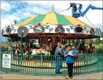  ??  ?? Austin Bishop pressure-washes the canvas tent above Charlie’s Carousel while owner Wayne Bishop talks to Fabby Solorzano, an assistant food service manager, at Bishop’s Pumpkin Farm in Wheatland on Wednesday.