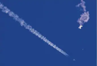  ?? Chad Fish/Associated Press ?? The remnants of the suspected Chinese spy balloon drift above the Atlantic Ocean, just off the coast of South Carolina, with a fighter jet and its contrail seen below it Saturday.