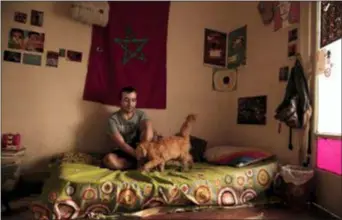  ?? NARIMAN EL-MOFTY — THE ASSOCIATED PRESS ?? In this Thursday photo, Yassin Mohammed sits with a cat in an apartment he shares, in Cairo, Egypt.