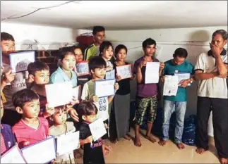  ?? SUPPLIED ?? A rejected group of 29 Montagnard­s pose with signs reading “please help us” in September 2017.