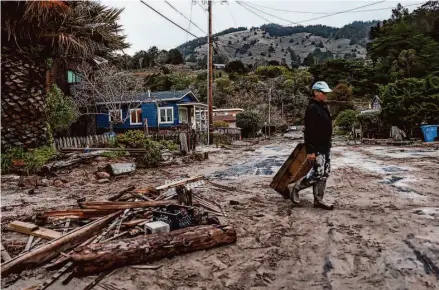  ?? Gabrielle Lurie/The Chronicle ?? Dino Colombo salvages debris after the exterior of his home was partly damaged during days of rain at Stinson Beach in Marin.