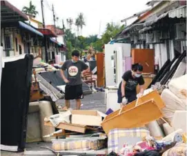  ??  ?? Kenneth Sim and his friend Kim Khaw discarding their damaged furniture at Taman Sri Rambai in Bukit Mertajam yesterday.