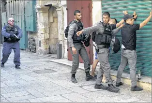  ?? AP PHOTO ?? Israeli border police officers body-search Palestinia­ns in Jerusalem’s Old City, Friday. Three Palestinia­n assailants opened fire on Israeli police from inside a major Jerusalem holy site Friday, killing two officers before being shot dead, police said.