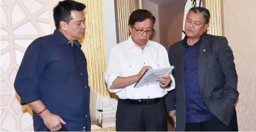  ?? — Photos by Tan Song Wei ?? Abang Johari double-checking some documents while observed by his principal private secretary Wan Khalik Wan Muhammad (left) and State Secretary Tan Sri Datuk Amar Morshidi Abdul Ghani (right).