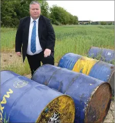  ??  ?? Cllr Paul Bell at the oil drums dumped in a field on the link road between the Donore Road and Platin Road.