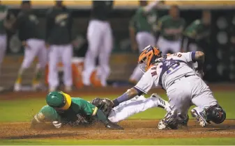  ?? Ben Margot / Associated Press ?? The A’s Ramon Laureano dives as catcher Martin Maldonado applies the tag in the ninth. Laureano initially was called out, but a video review overturned the ruling.