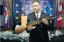  ?? Ted Rhodes/calgary Herald ?? Calgary Police Staff Sgt. Geoff Gawlinski holds the weapon and stands in front of the drugs and other items seized last Thursday.