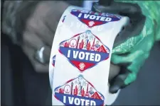  ?? STEVE MARCUS — LAS VEGAS SUN VIA AP, FILE ?? In this Saturday, Oct. 17, 2020, file photo a poll worker displays “I Voted” stickers during the first day of early voting in Las Vegas. Democrats have kept Nevada in their column in every presidenti­al election since 2004. But political strategist­s and organizers on the ground warn Nevada is still a swing state.