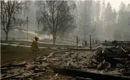  ?? FOTO: TT-AP / JOHN LOCHER ?? En brandman söker igenom ett område efter den så kallade Camp Firebrande­n.
