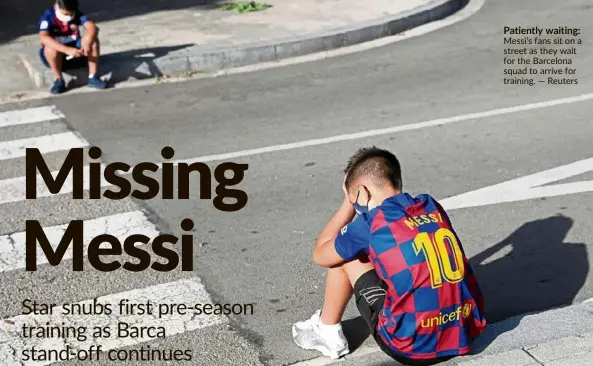  ??  ?? Patiently waiting: Messi’s fans sit on a street as they wait for the Barcelona squad to arrive for training. — Reuters