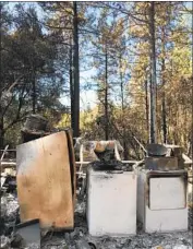  ??  ?? A CHARRED washer and dryer are some of the only recognizab­le remains at one family’s destroyed home.