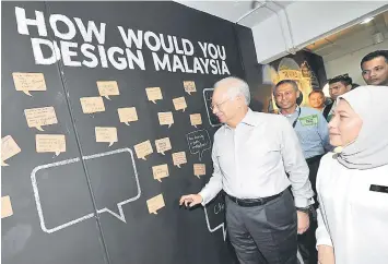  ??  ?? Najib (left) looking at the notes pasted on the board after the ‘Design Thinking’ dialogue. Nancy is seen at right. — Bernama photo