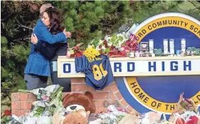  ?? JAKE MAY/THE FLINT JOURNAL VIA AP ?? Gov. Gretchen Whitmer embraces Oakland County Executive Dave Coulter as the two leave flowers and pay their respects Thursday at Oxford High School in Oxford, Mich. The parents of a teen accused of killing four students at a Michigan high school were charged with involuntar­y manslaught­er Friday.