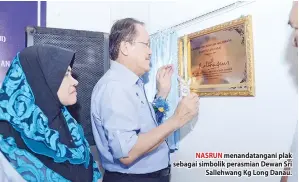 ??  ?? NASRUN menandatan­gani plak sebagai simbolik perasmian Dewan Sri Sallehwang Kg Long Danau.