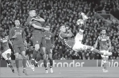  ?? JON SUPER / ACTION IMAGES VIA REUTERS ?? Napoli’s Arkadiusz Milik attempts an acrobatic volley as Liverpool’s Dejan Lovren defends during Tuesday’s Champions League Group C match at Anfield. The Reds won 1-0 to qualify for the last 16.